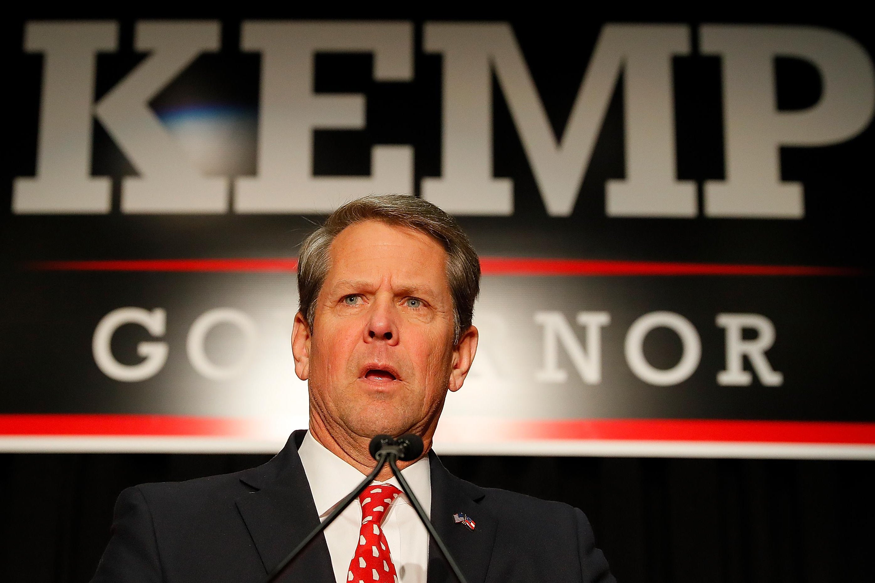 Brian Kemp in front of a Kemp/Governor sign.