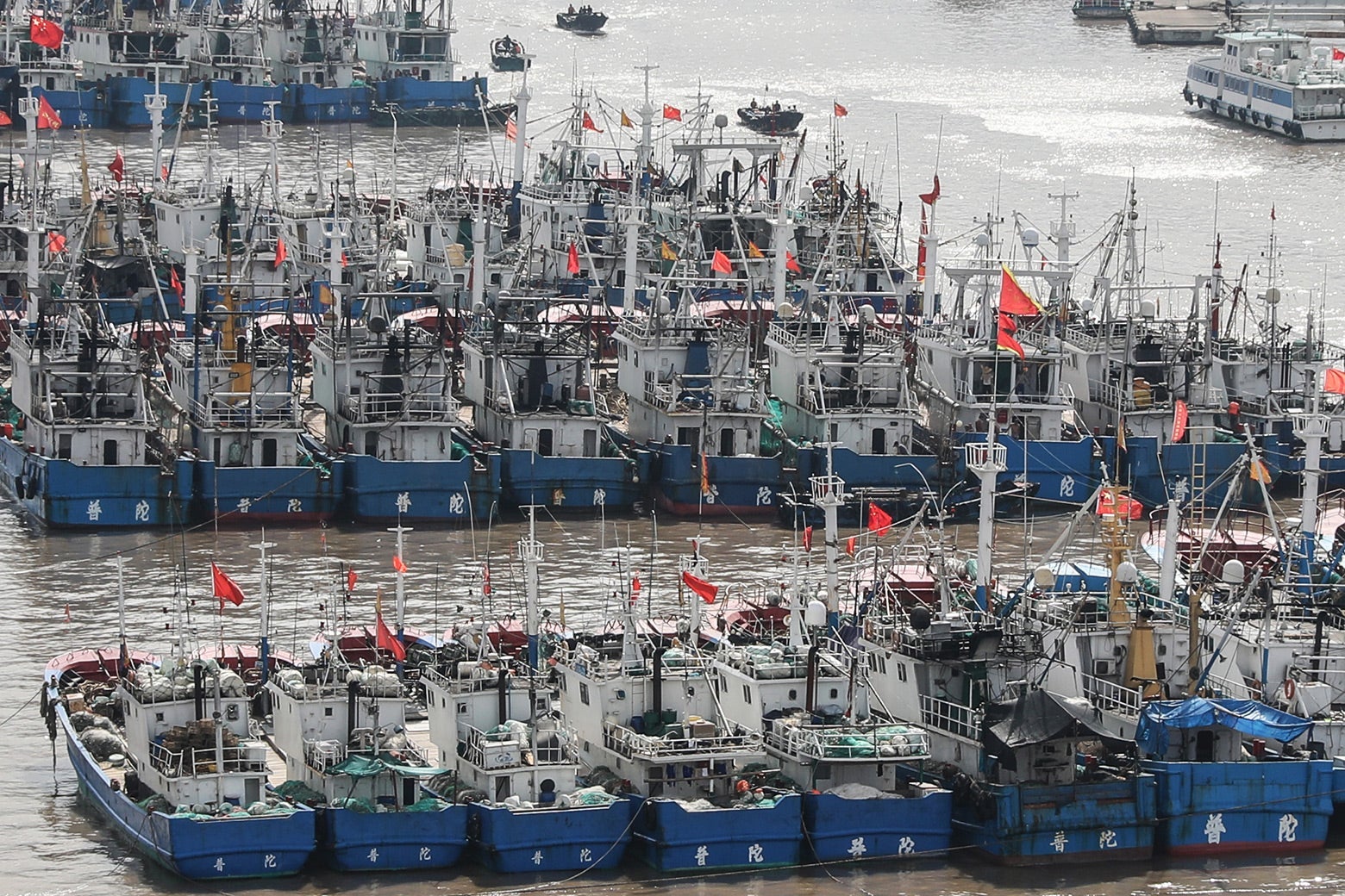Many blue and white boats side by side with Chinese flags.