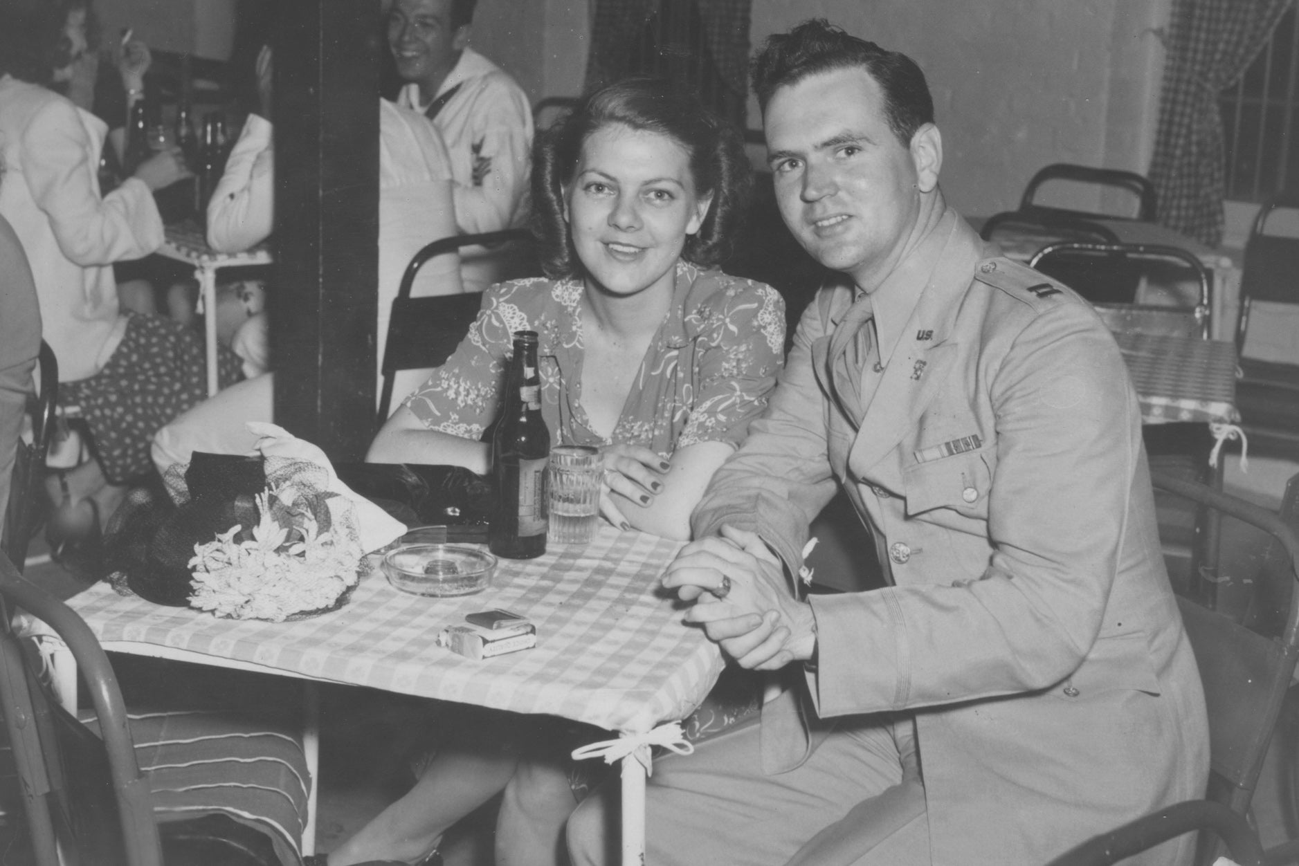 A couple smile at a restaurant table in a black and white photo.