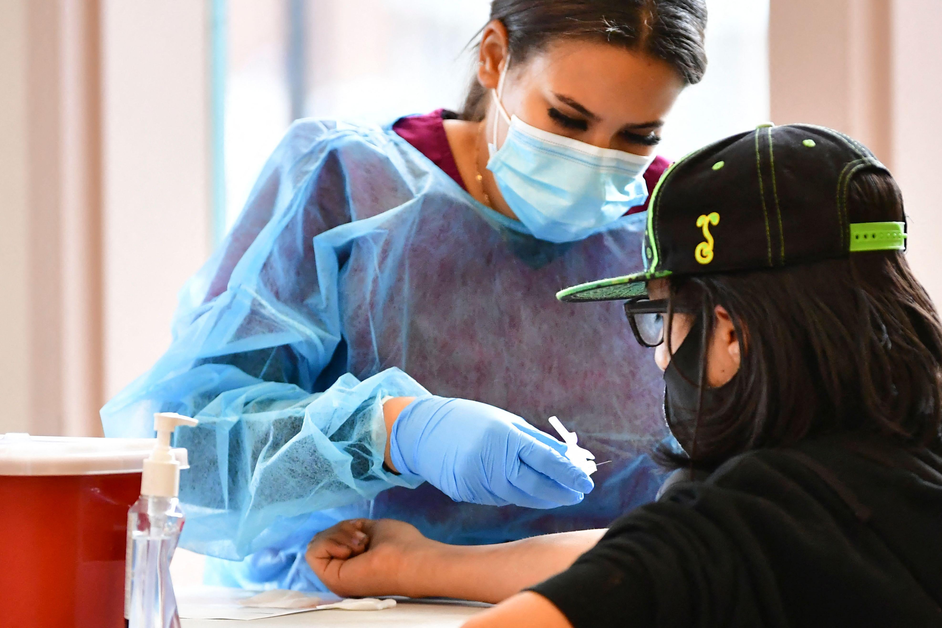 A phlebotomist wearing PPE draws blood for an antibody test in Santa Fe Springs, California, on April 21