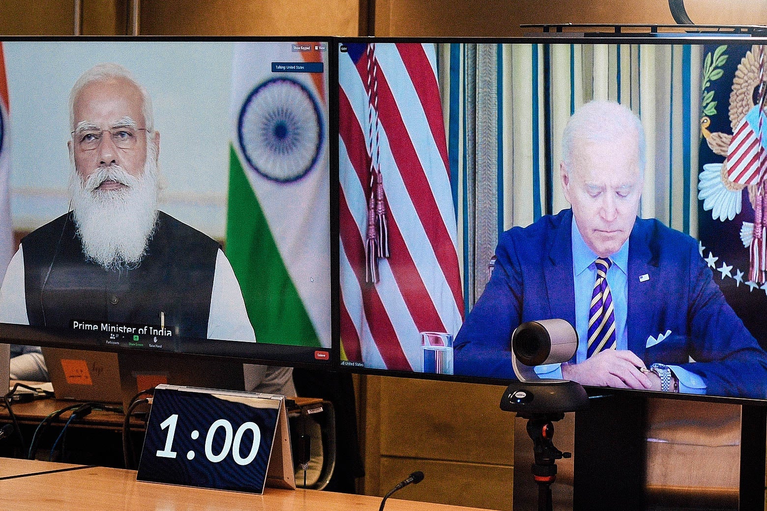 Modi and Biden seen in a videoconference on two TV screens.