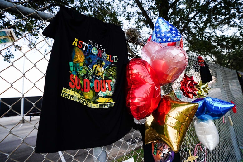 A black T-shirt and red, gold, blue, and white balloons attached to a fence. The shirt says "ASTROWORLD SOLD OUT."