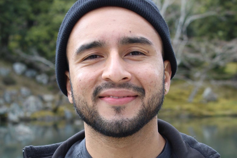 A smiling young man with a beard looks directly into the camera.