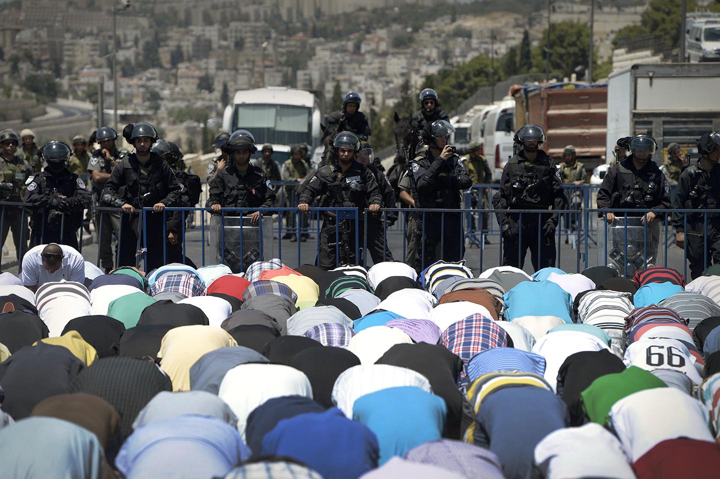 Palestinians perform Friday prayer on the street, outside the Al-Aqsa Mosque after Israeli police.