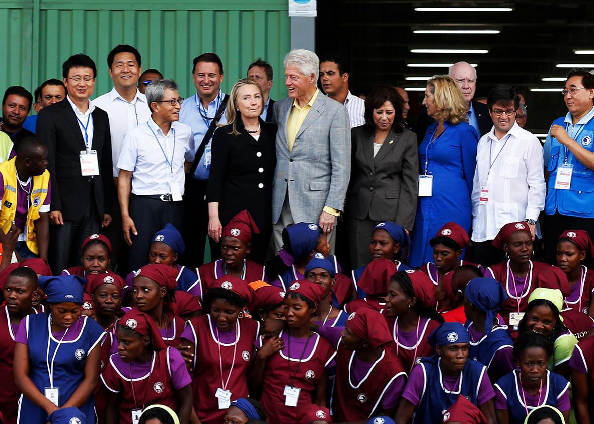 Former US president Bill Clinton and his wife, US Secretary of State Hillary Clinton, pose with workers at the grand opening cermony of the new Caracol Industrial Park in Caracol, Haiti, on October 22, 2012.  