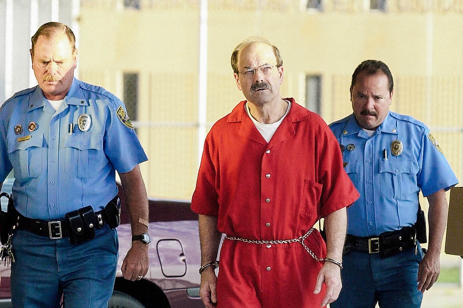 Dennis Lynn Rader wearing prison jumpsuit and handcuffs.