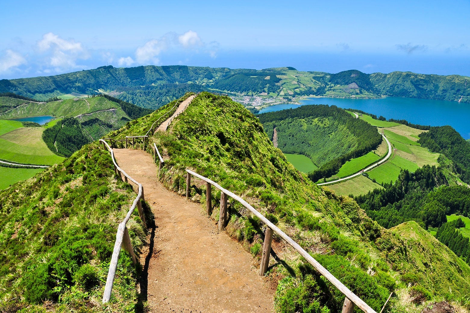 Landscape shot of a path through the hills of the Azores with lush greenery and clear blue skies.
