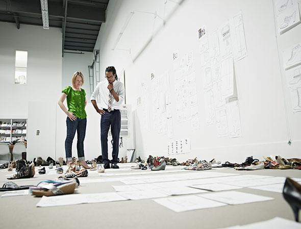 Designers examining sample shoes on floor.