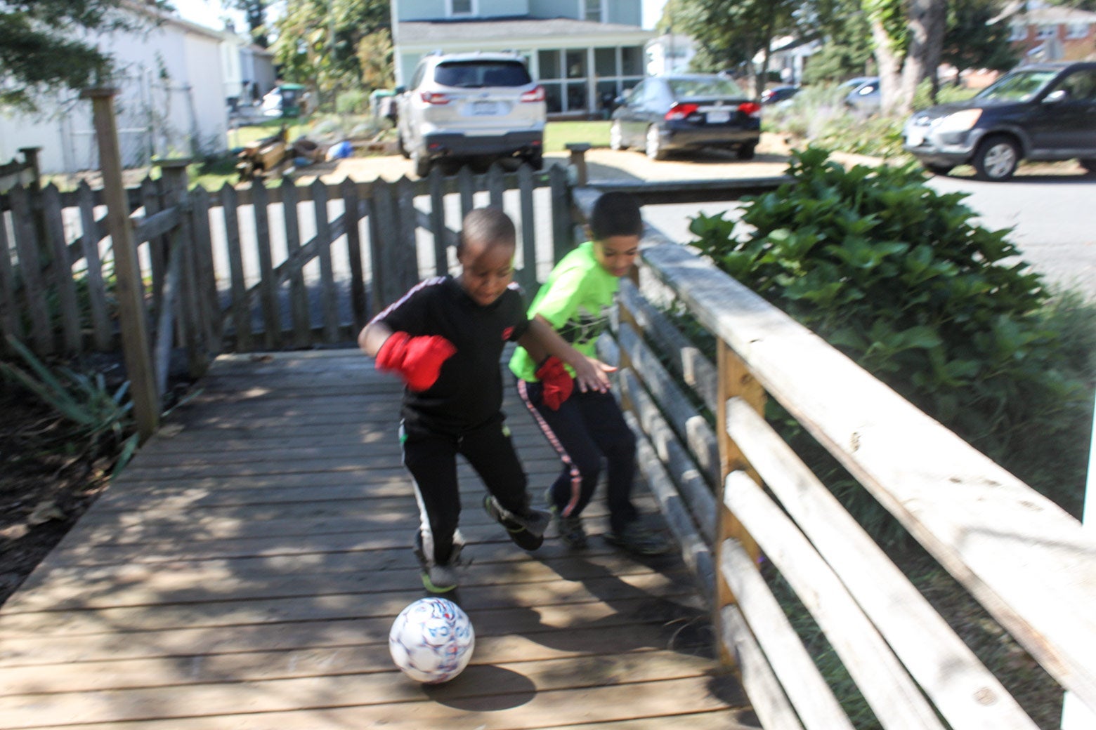 Two boys play with a soccer ball in a fenced-in area.