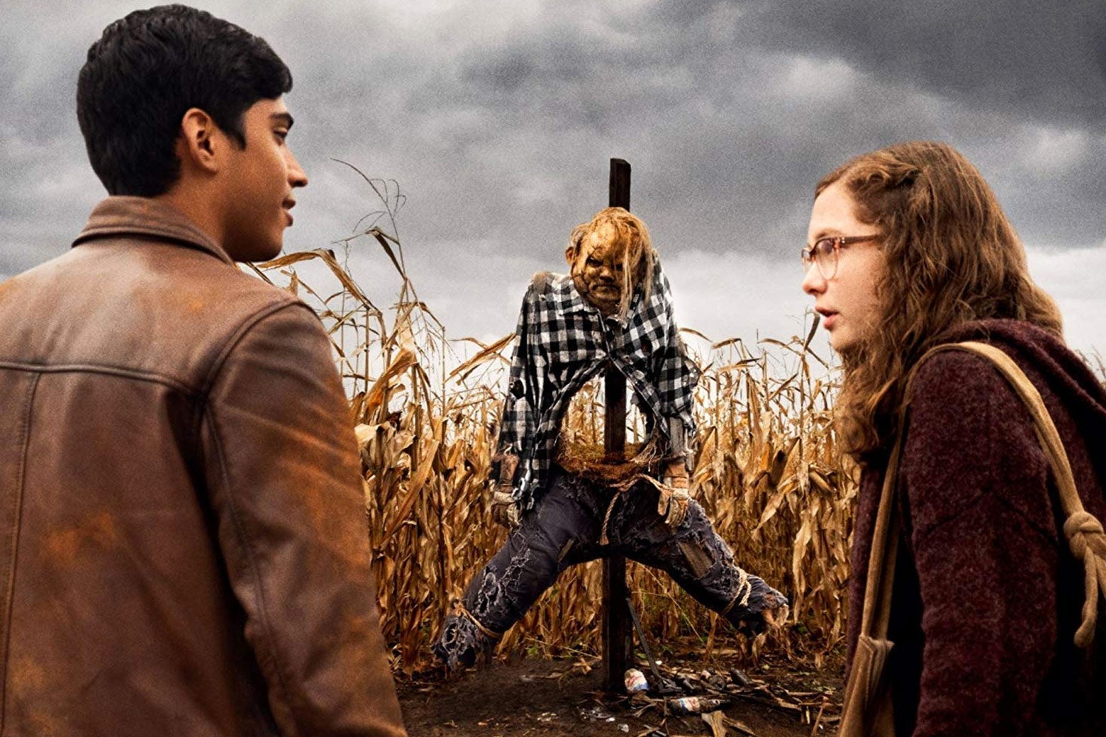 In a scene from the film, two kids stand in front of a menacing scarecrow in a cornfield.