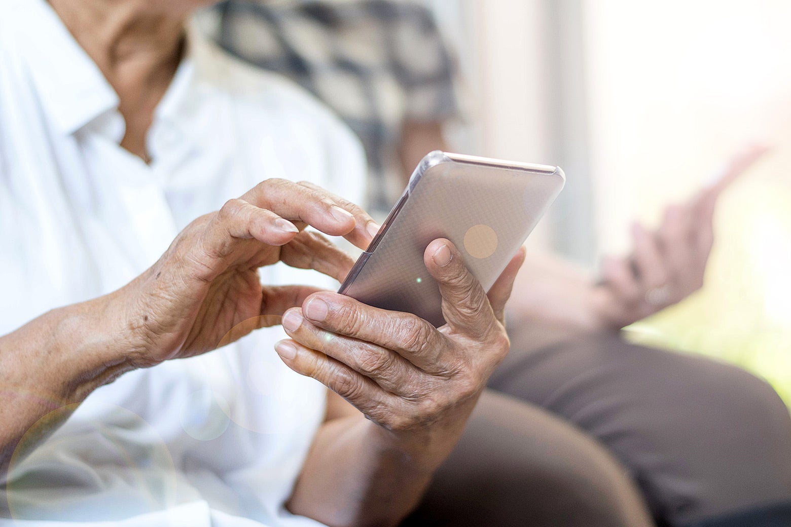 An elderly person's hands hold a smartphone