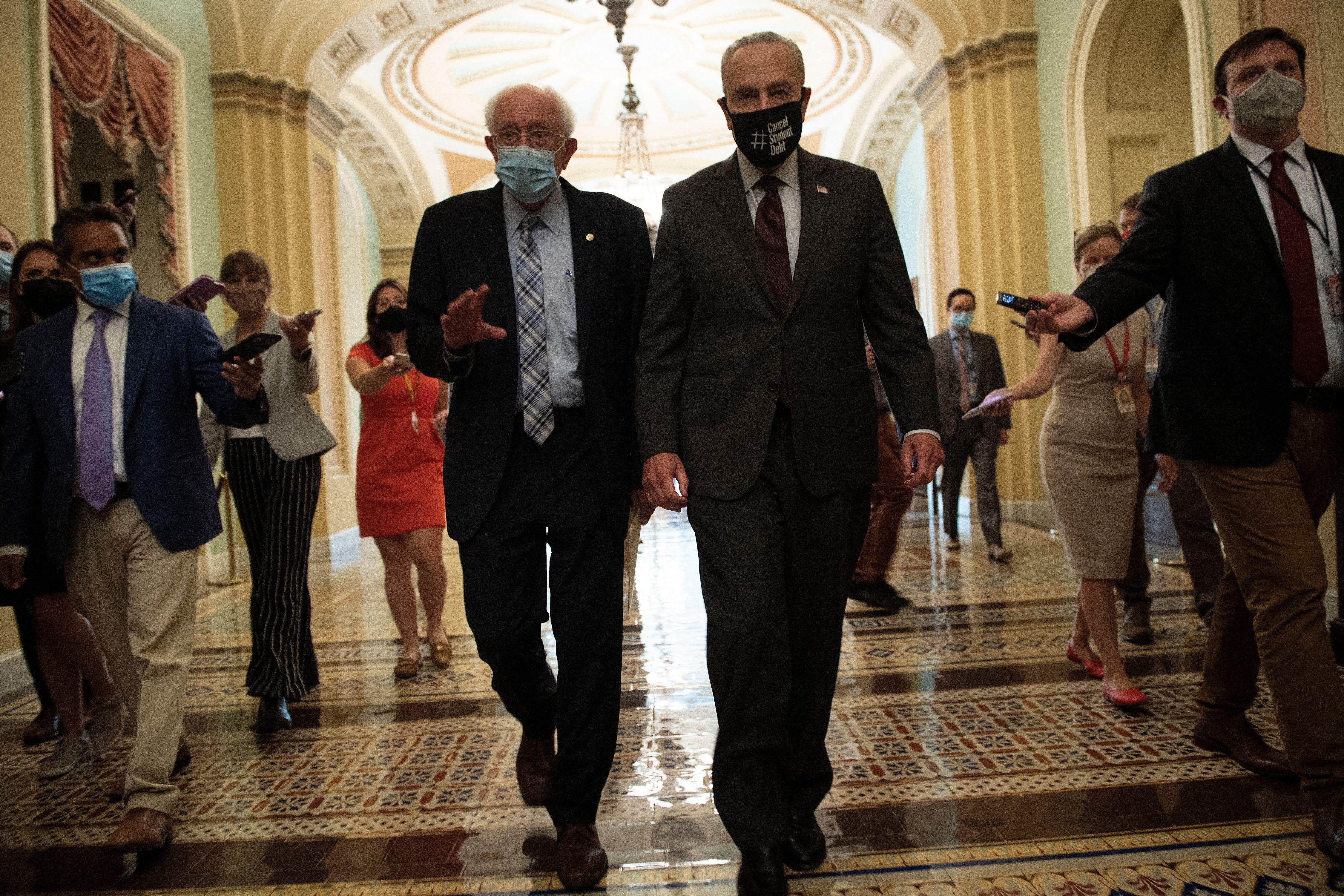 Senator Bernie Sanders and Senate Majority Leader Chuck Schumer walking down a hallway on Capitol Hill as the Senate moves toward a vote on infrastructure funding August 9, 2021, in Washington, DC. 