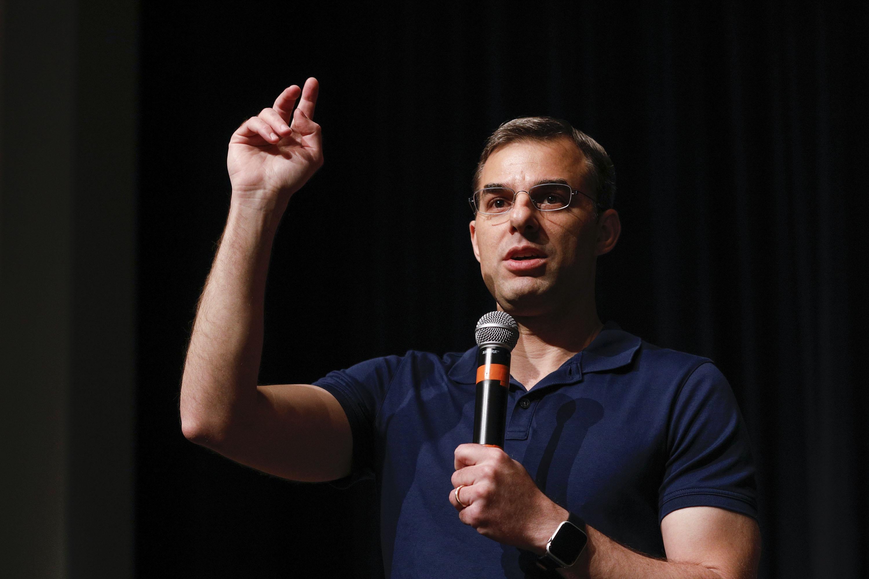 Rep. Justin Amash holds a microphone and gestures.