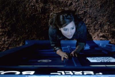A woman climbs up a TARDIS in a still from the show.