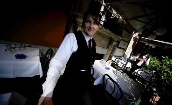 A waitress stands in front of a restaurant in downtown Rome on Nov. 2, 2011