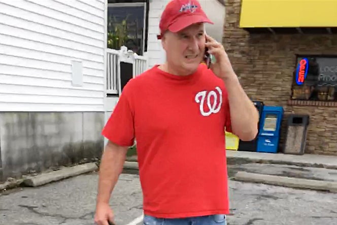 Judge, wearing a red Washington Nationals shirt, speaks on a phone while walking through a parking lot.