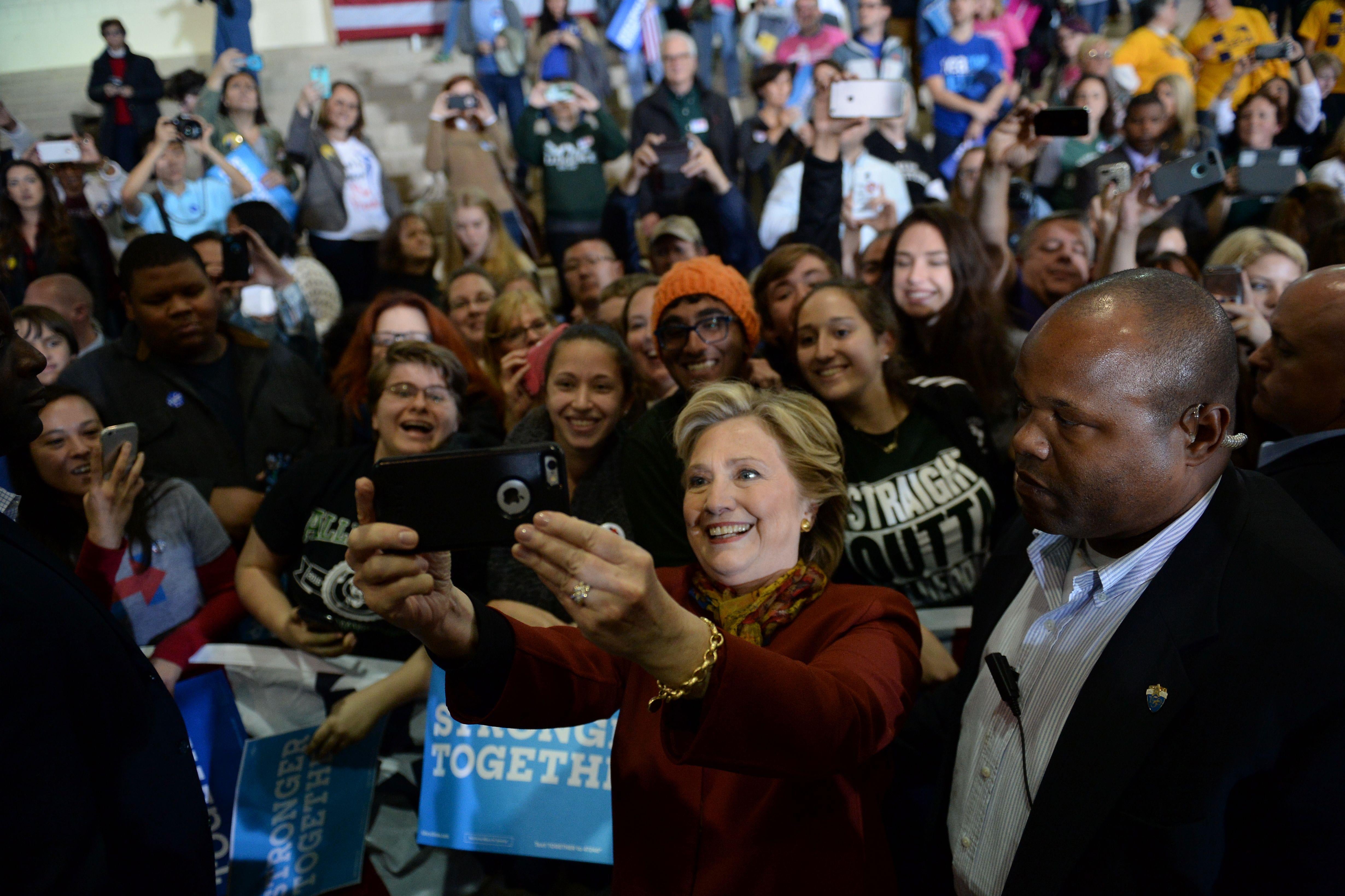 Democratic presidential nominee Hillary Clinton takes a selfie with supporters during a campaign event with her running mate Tim Kaine, October 22, 2016 at Taylor Allderdice High School in Pittsburgh, Pennsylvania. / AFP / Robyn BECK        (Photo credit should read ROBYN BECK/AFP/Getty Images)