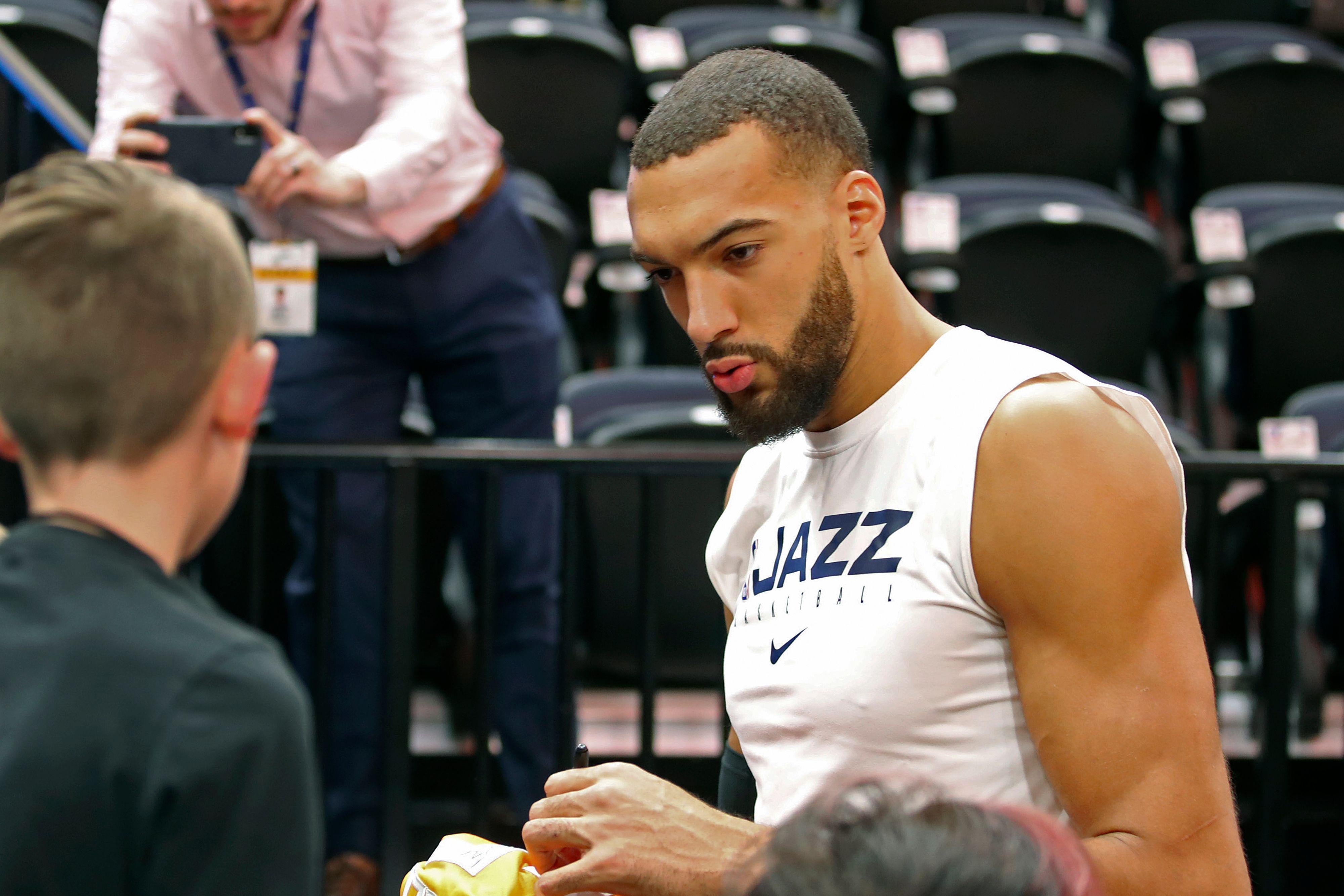 Gobert stands in the arena, signing autographs for fans