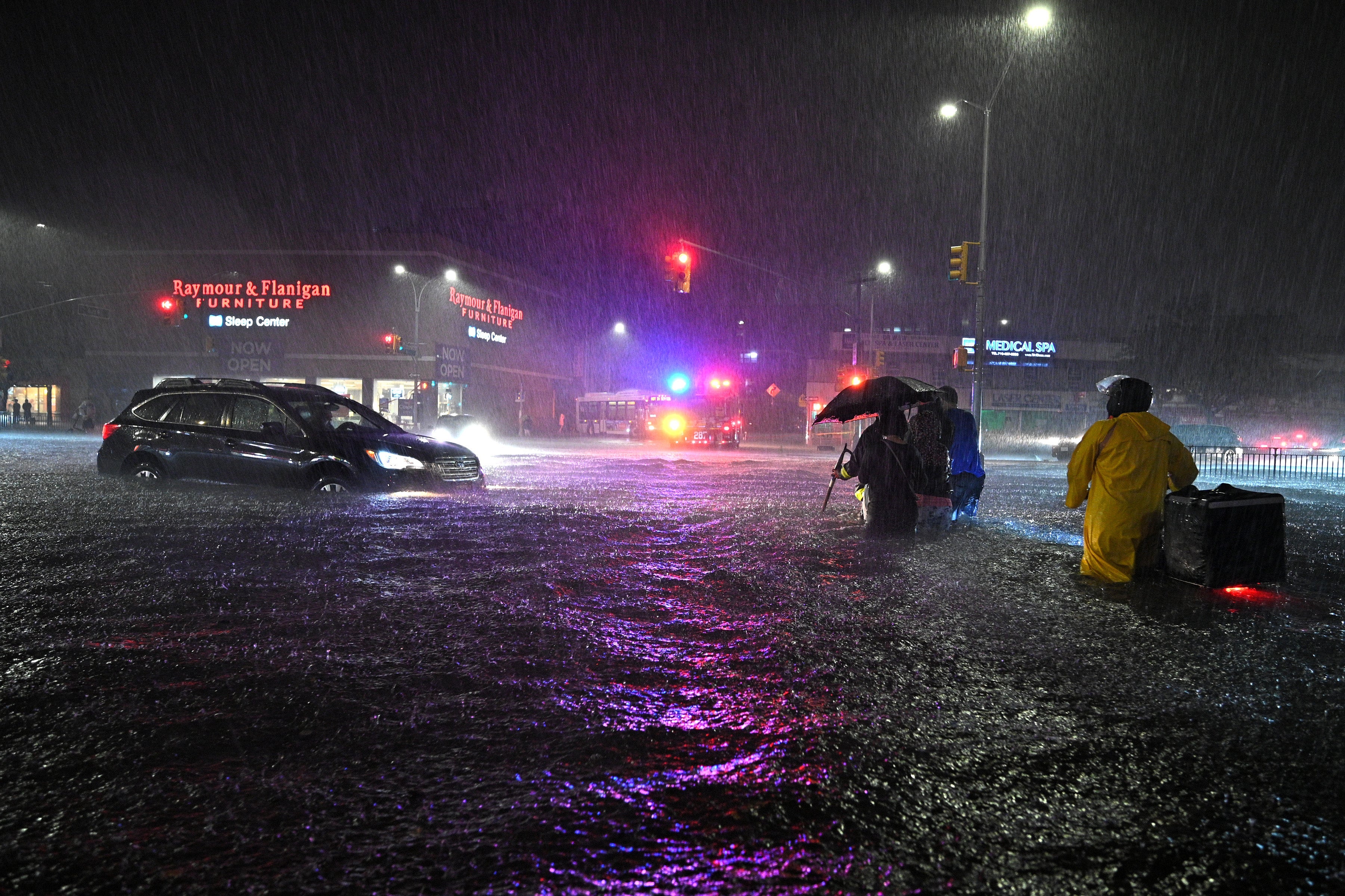 Members of the FDNY help people across Queens Boulevard through flash flood waters.