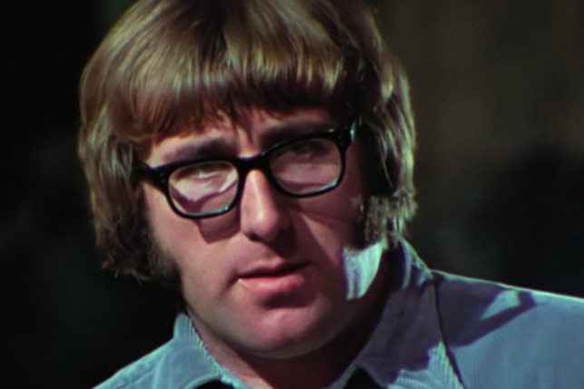 A man with a mop top haircut wearing black glasses