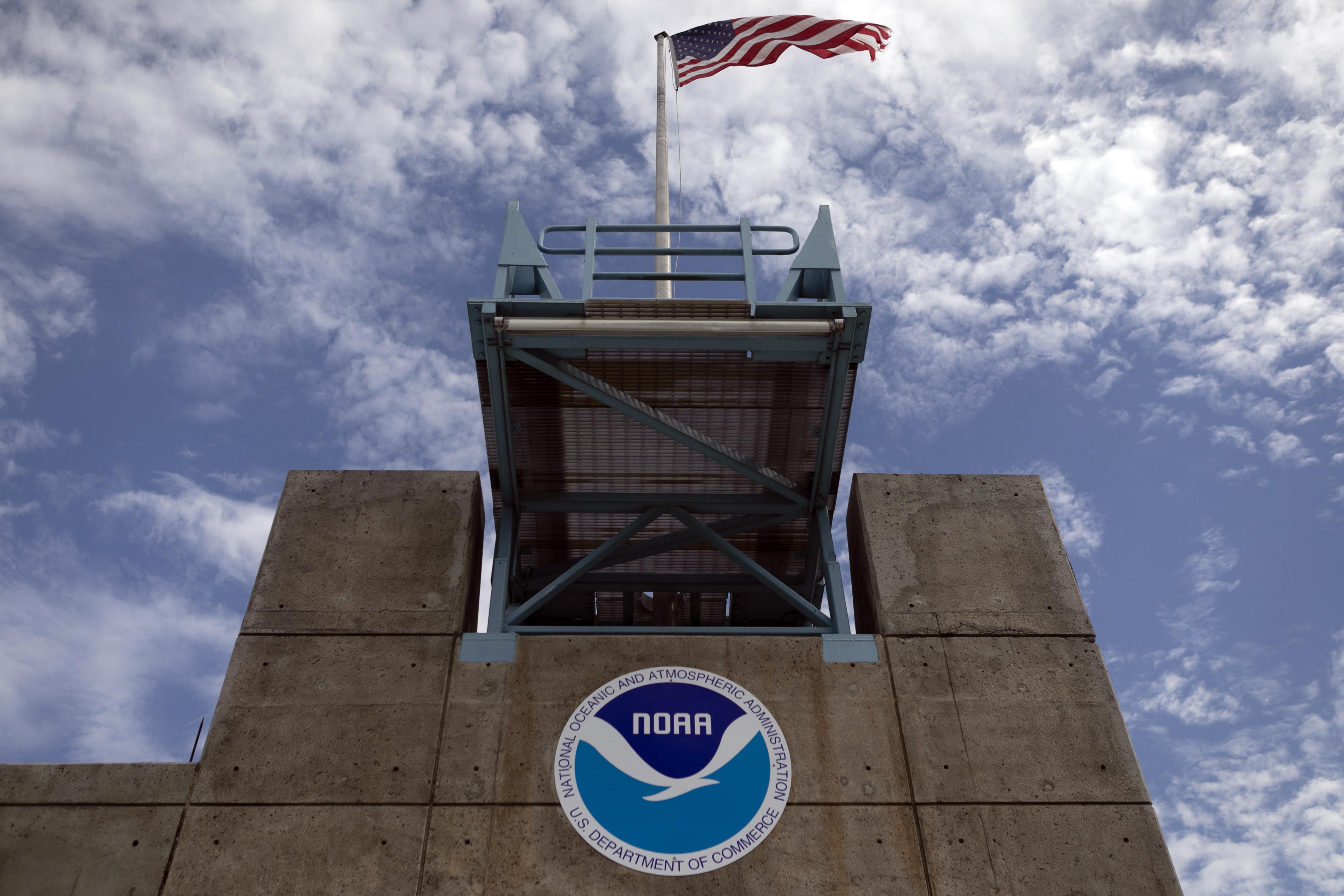 A cement building with the NOAA logo on the front and a flag flying over top.