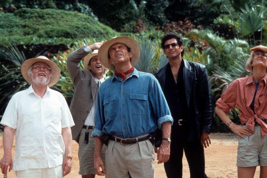 Several actors in safari clothes shade their eyes to look at a large thing off camera.
