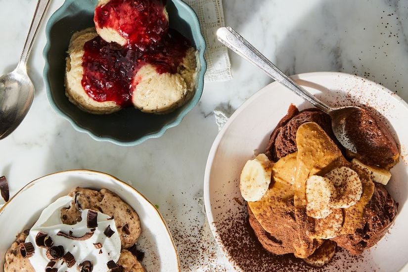 Bowls of ice cream. One is topped with strawberry jam, another with peanut butter, bananas, and cocoa powder. A third has whipped cream and chocolate shavings.