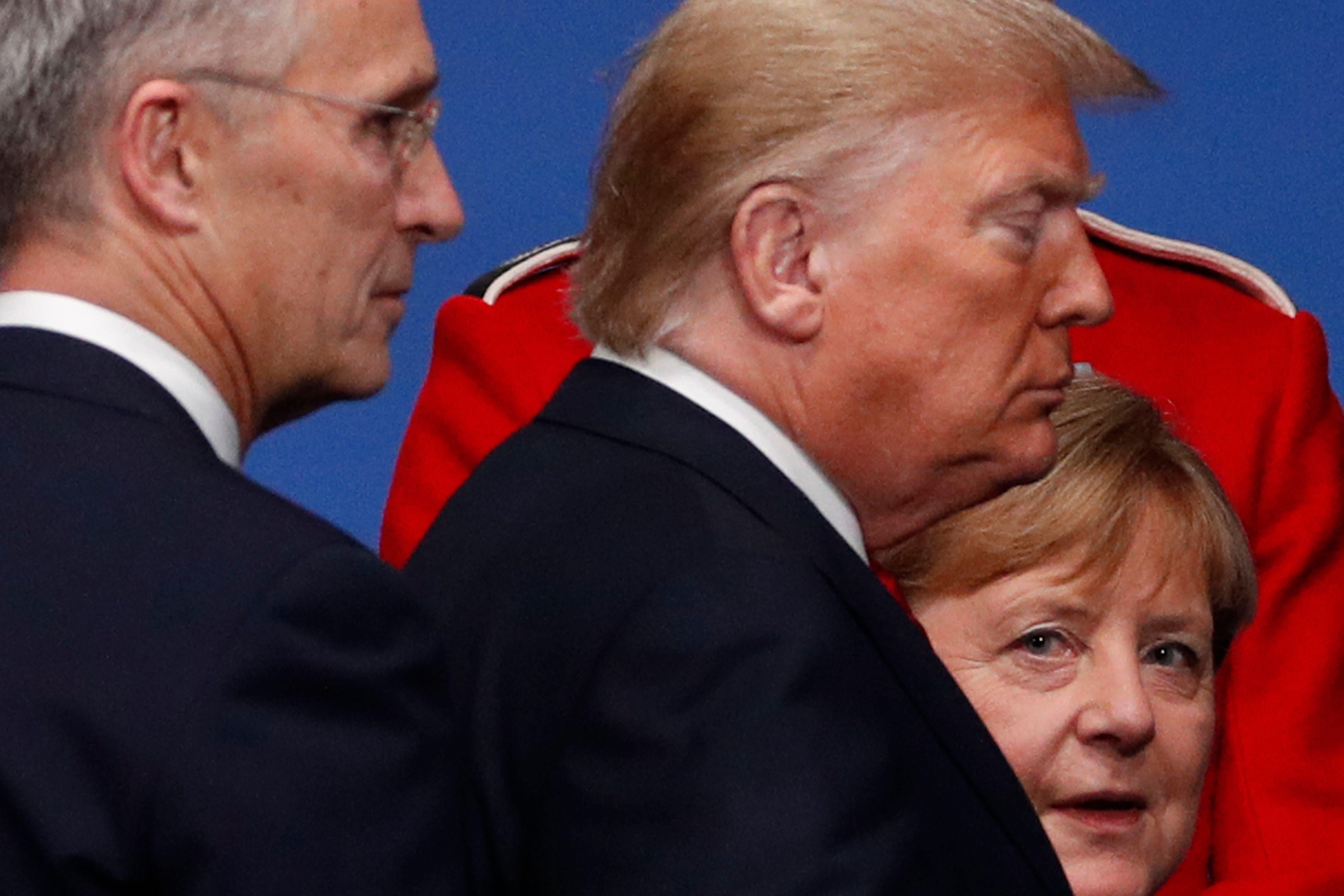 Merkel looks toward the camera as Trump and Stoltenberg walk past her.
