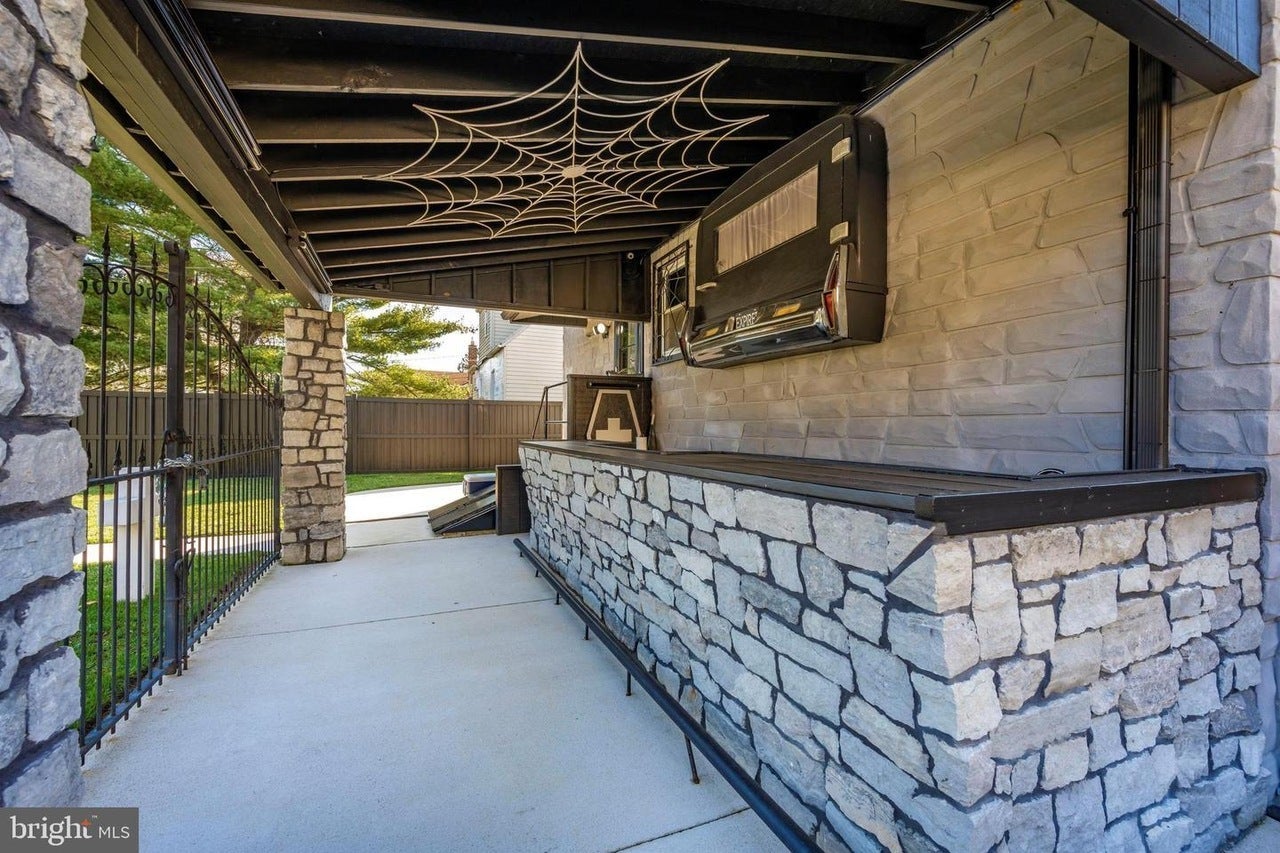 An outdoor stone and granite wet bar decorated with cobwebs and the back of a hearse.