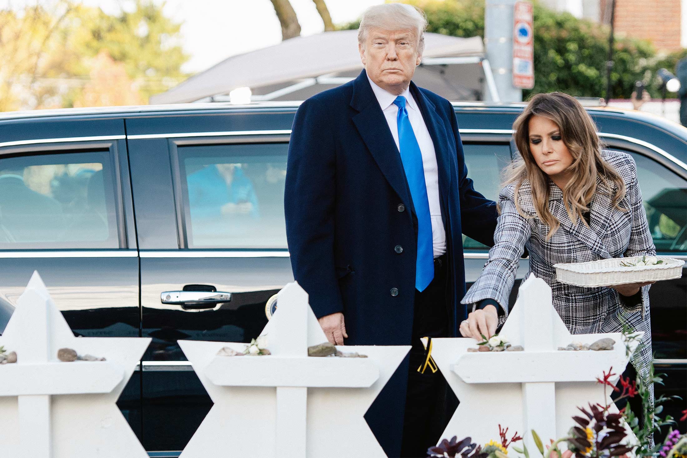 Donald Trump and Melania Trump place stones and flowers on a memorial.