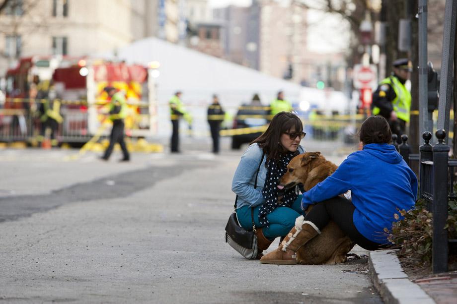 Two women sit with their dog near the scene after two explosions interrupted the running of the Boston Marathon in Boston, Massachusetts.