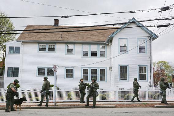 SWAT team members stand in front of a house while looking for 19-year-old bombing suspect Dzhokhar A. Tsarnaev, during a door-to-door search on April 19, 2013, in Watertown, Mass.