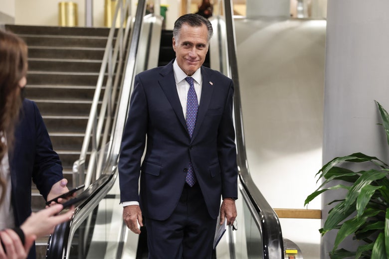 Mitt Romney smiling sheepishly as he descends an escalator in the Senate subway