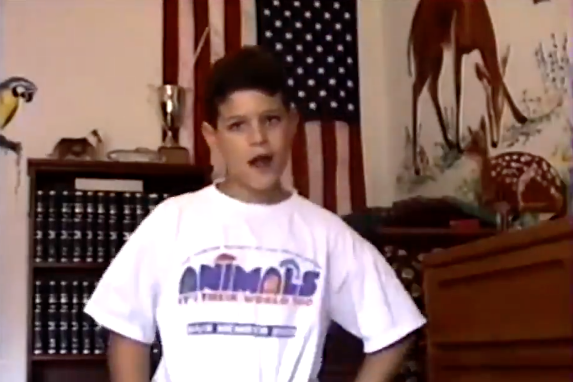 The author, as a 9-year-old boy, dancing in a large white T-shirt with his hands on his hips and his head slightly tilted. An American flag is on the wall in the background.