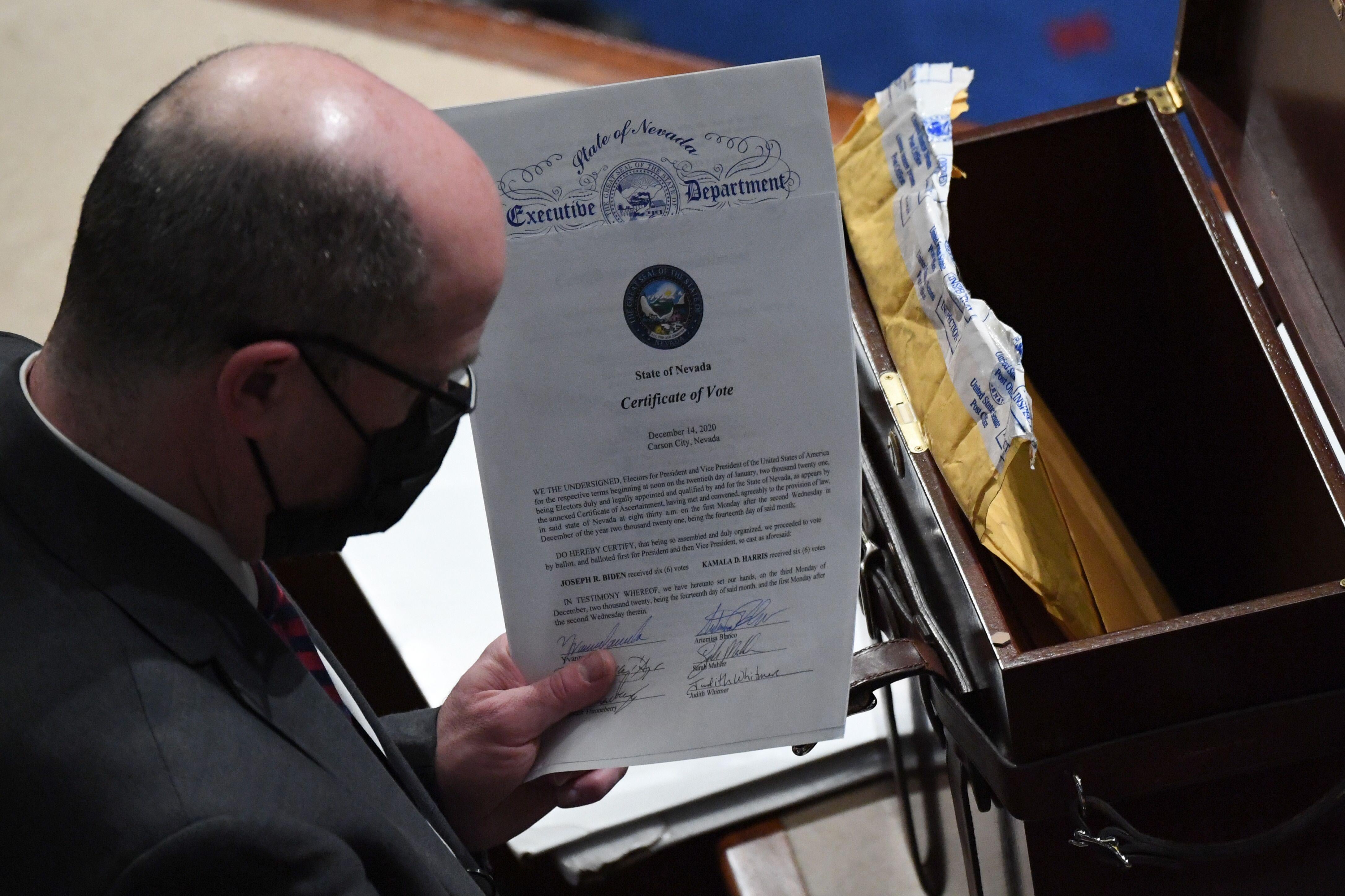 A bald man in a mask and glasses holds an official-looking document.