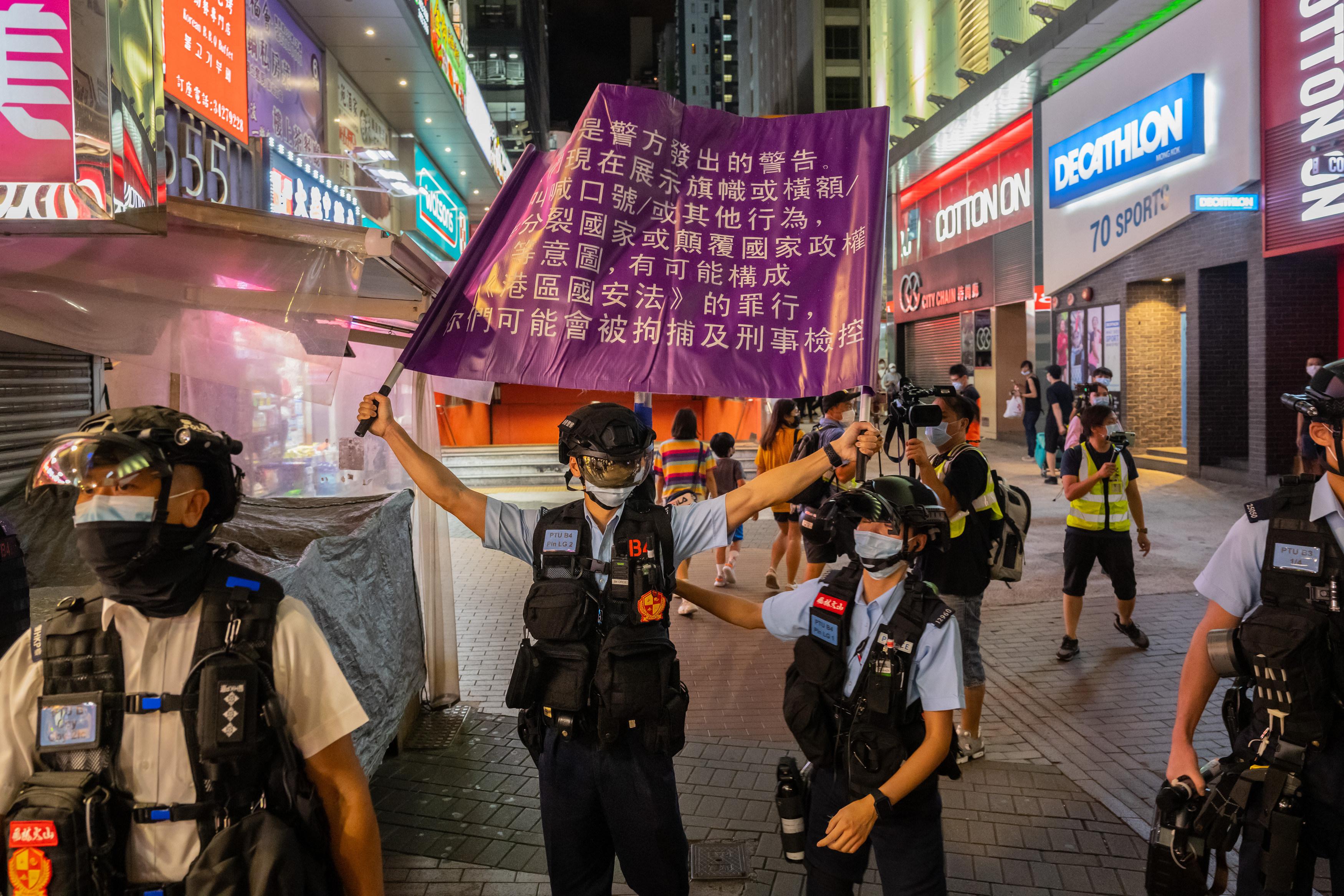 Police raise a purple flag with Chinese characters on it.