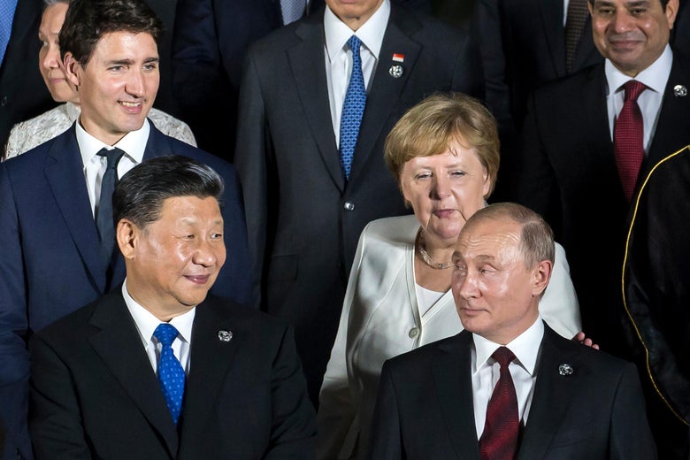 Vladimir Putin looks back at Angela Merkel as Justin Trudeau, Xi Jinping, and Abdel Fattah el-Sisi look on during a photo session.