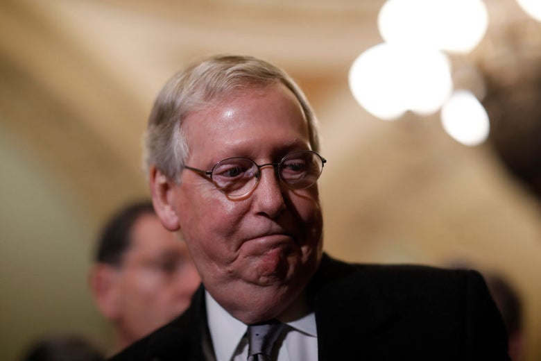 McConnell smiles and looks toward the floor.