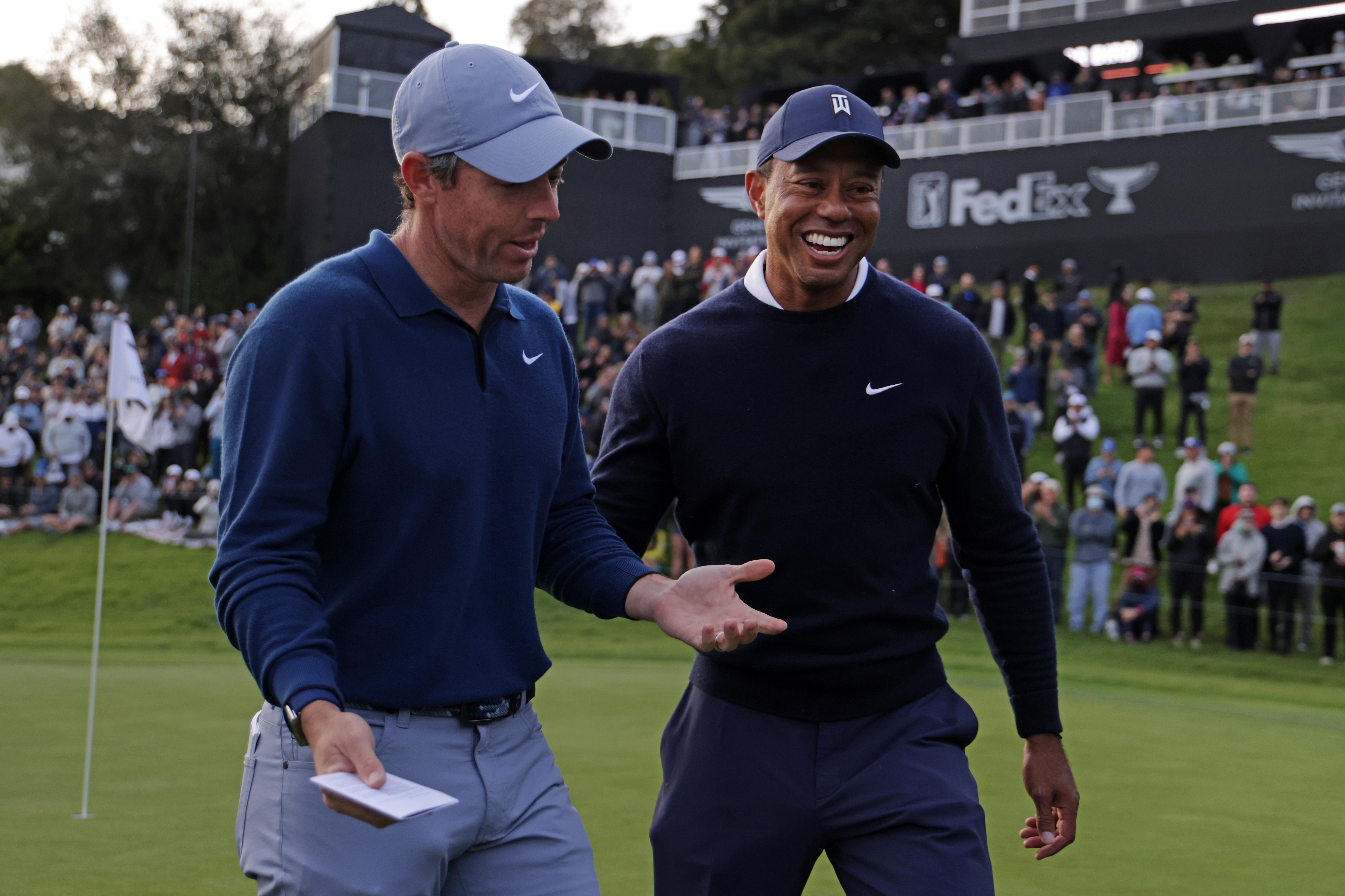Rory smiling and shrugging as Tiger pats him on the back and laughs