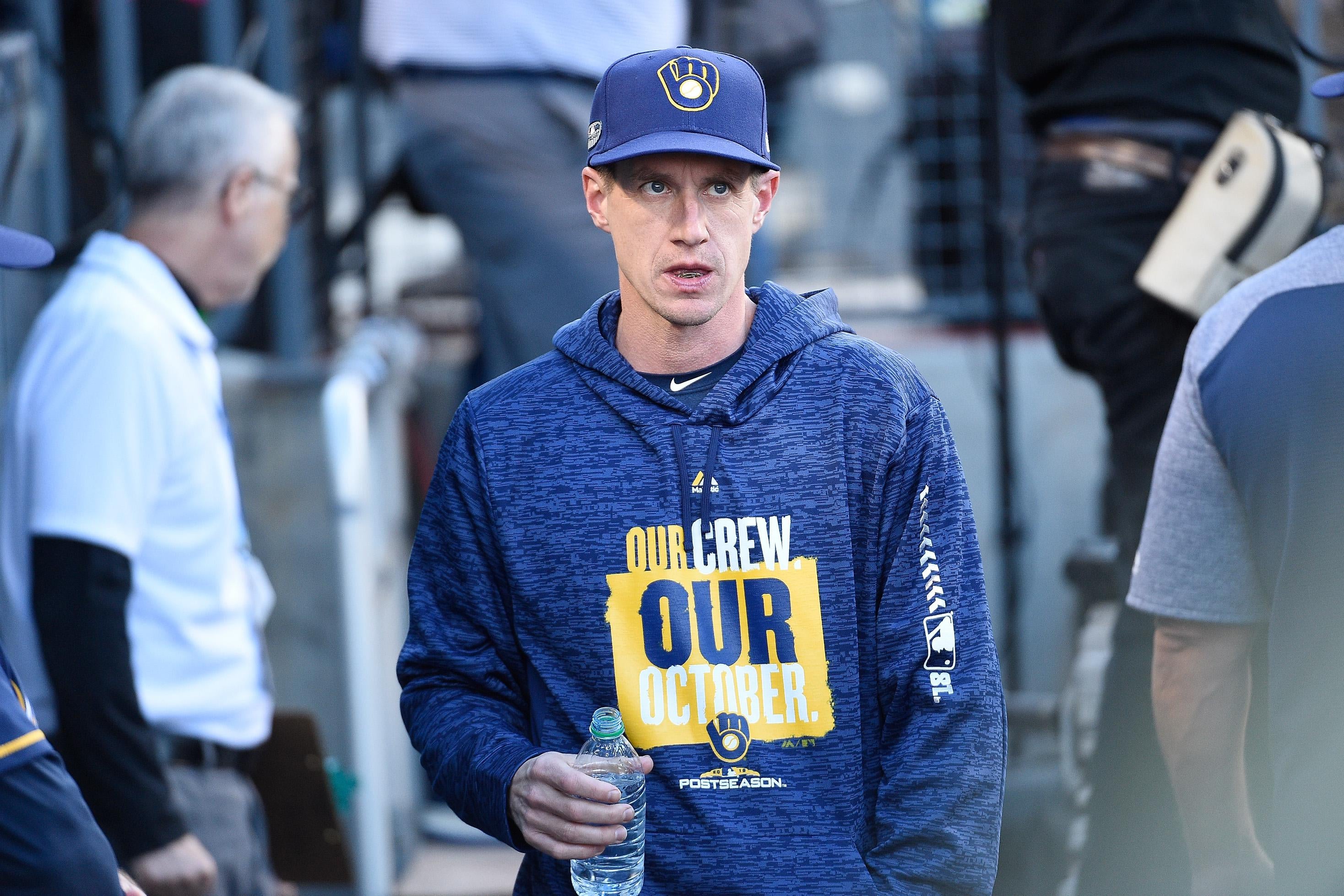 Brewers manager Craig Counsell in the dugout, holding a water bottle.