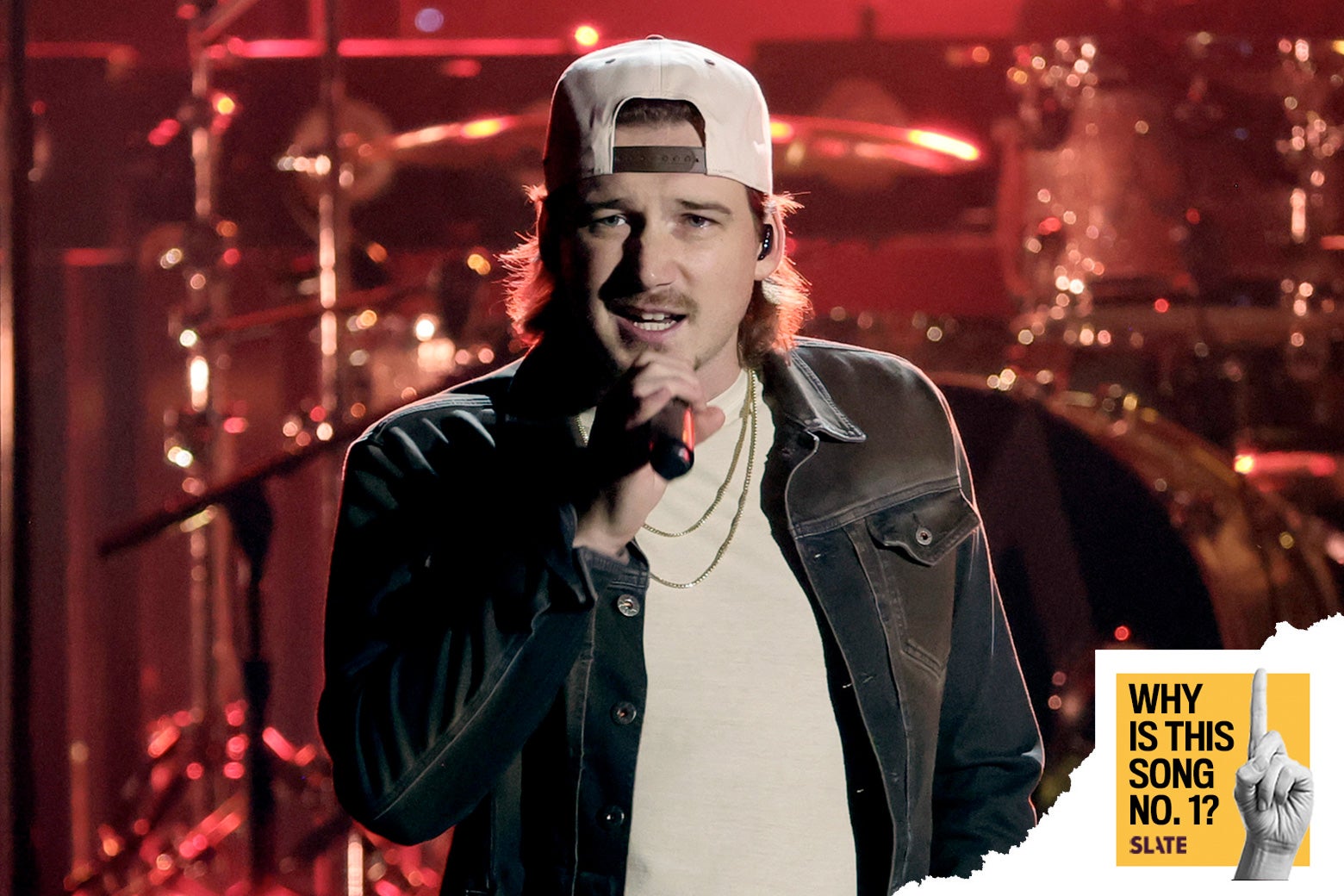 Morgan Wallen performs onstage at The 56th Annual CMA Awards at Bridgestone Arena on November 09, 2022 in Nashville, Tennessee, wearing a baseball cap and jean jacket. In front of him, the Why Is This Song No. 1 logo.