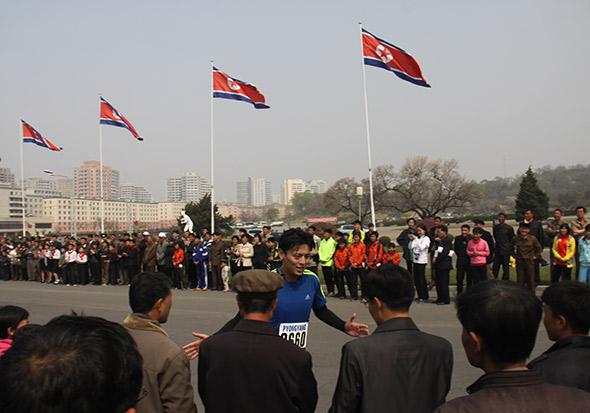 Amateur runner Peter Lau high-fives local marathon watchers as he finishes the final stretch of the half marathon, just outside Kim Il-Sung Stadium. Many of the tourist runners registered slower-than-usual times as they stopped to interact with locals lining the route.