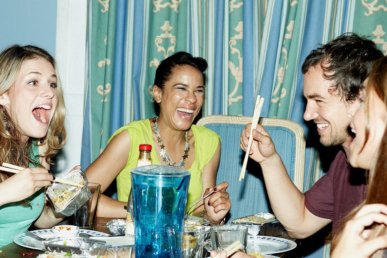 A group of people laughing around a dinner table.