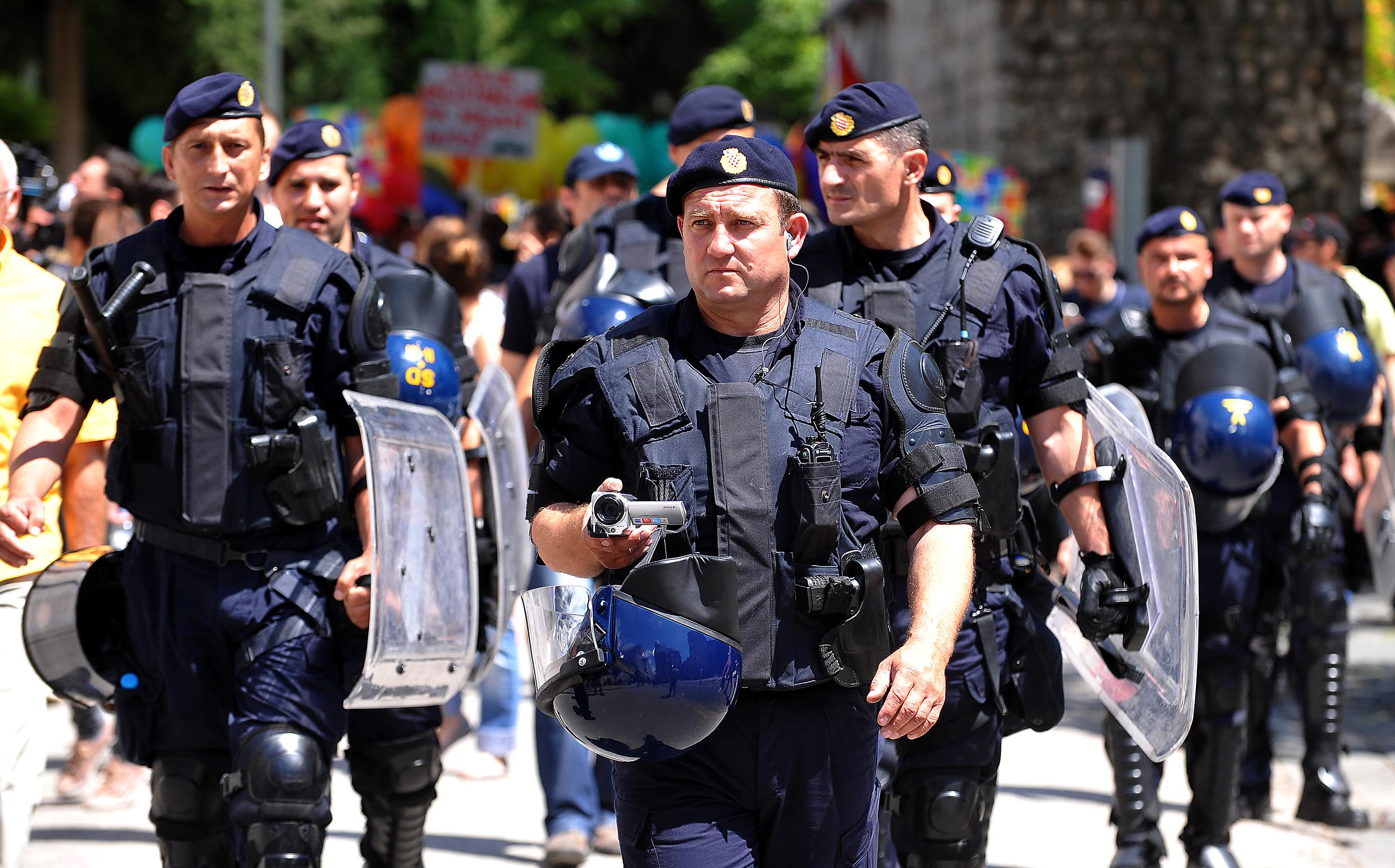 Police officers escort Gay Pride participants in the Croatian coastal city of Split on June 8, 2013.  A few hundred policemen, fully equipped in anti-riot gear, surrounded the 500 or so marchers. 