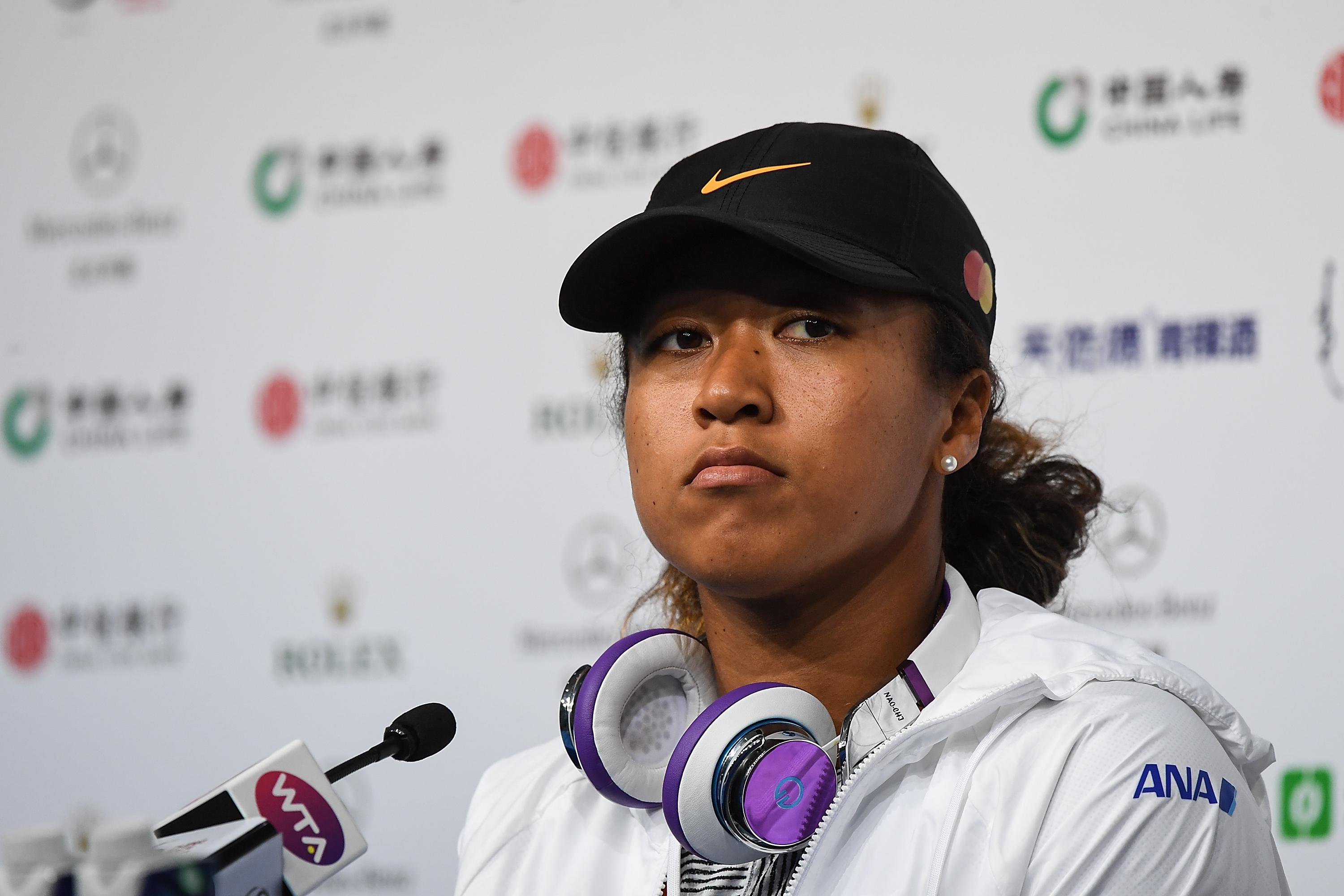 Naomi Osaka sits in front of a microphone.