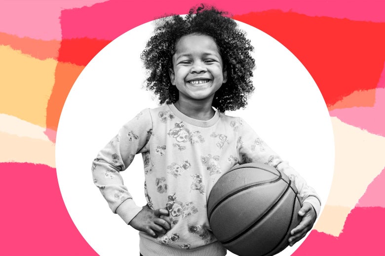 A 5-year-old girl smiles and holds a basketball.