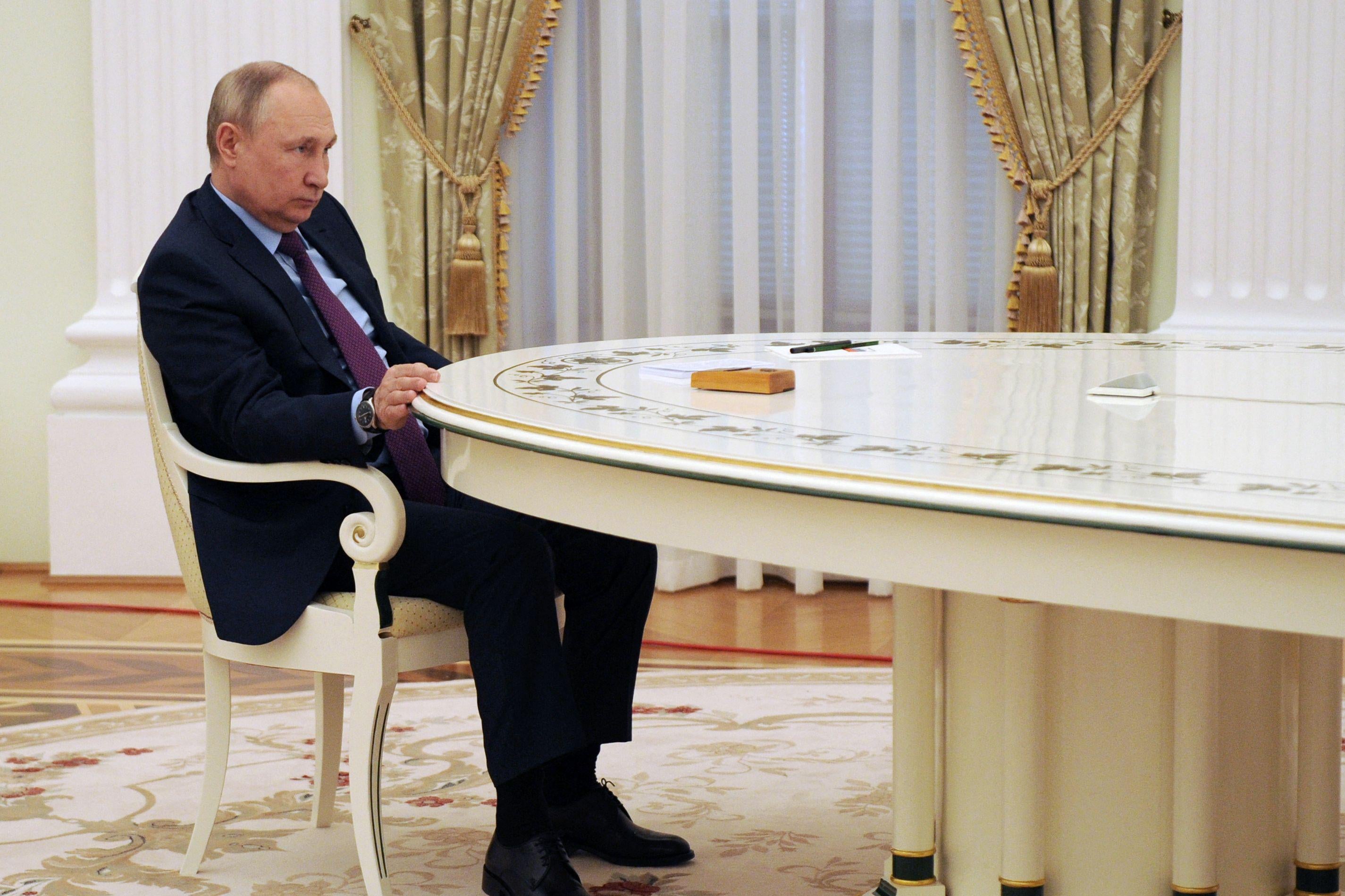 Putin sits at a large table.