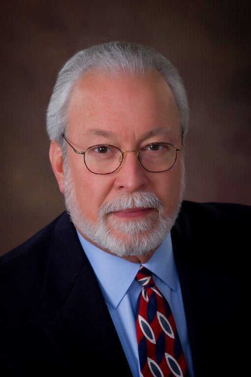 A white man with a beard wearing a suit and tie.