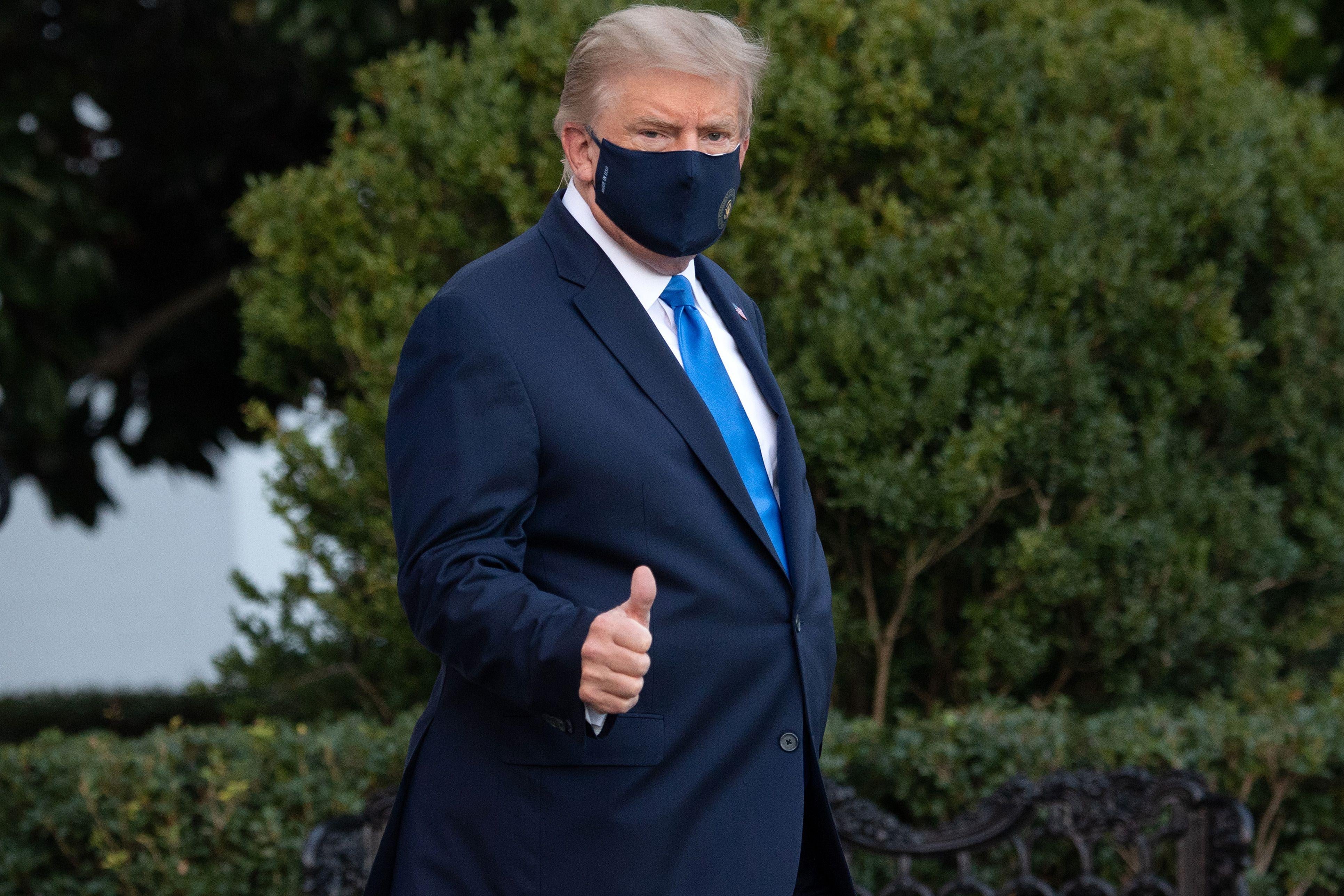 Trump gives a thumbs-up while wearing a mask.