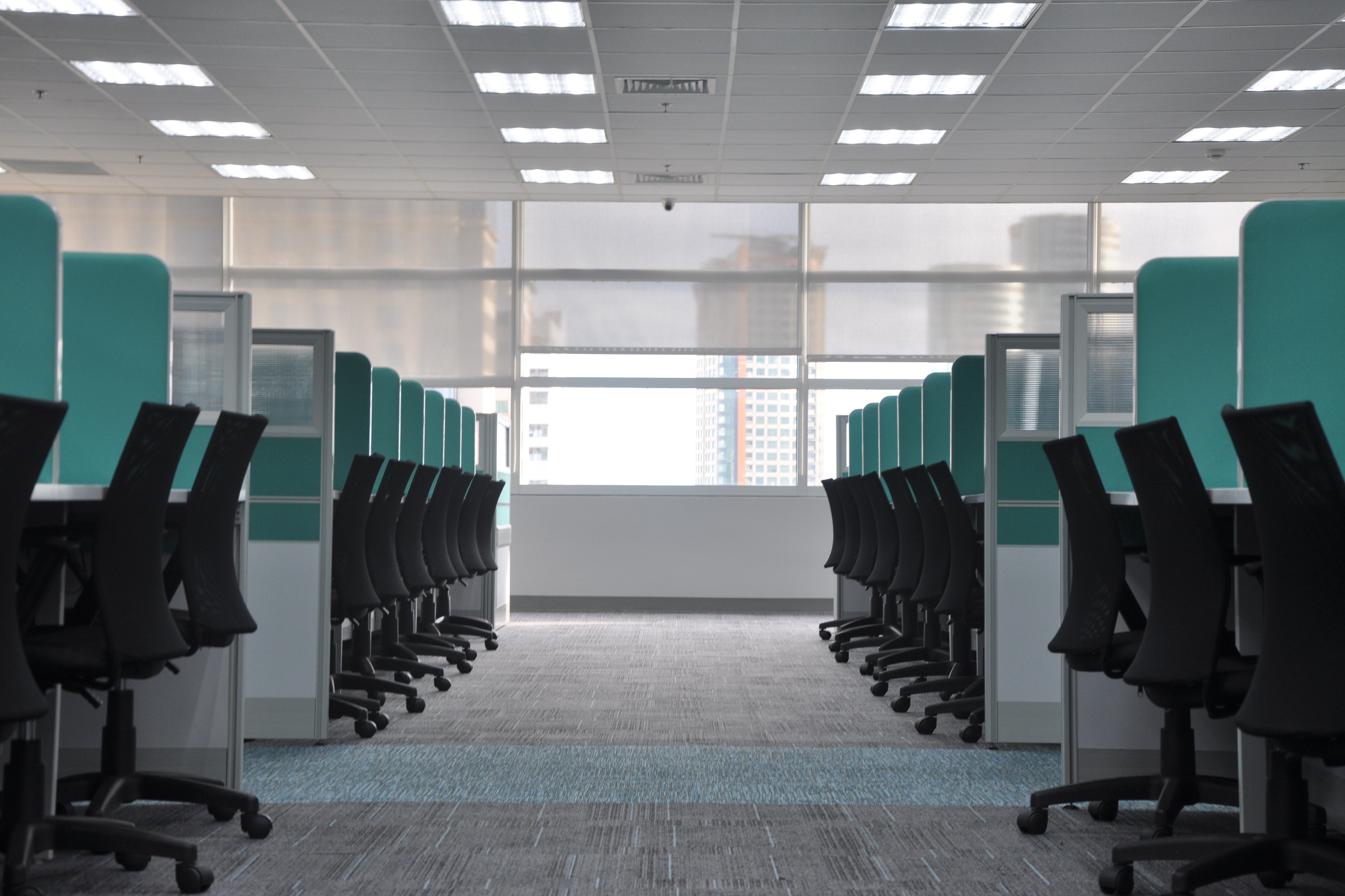 Two empty rows of cubicles and desk chairs